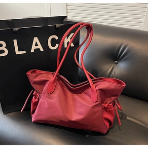 Détail du grand sac de voyage rose foncé avec cordons décoratifs sur un canapé en cuir