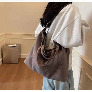 Detailed view of the brown canvas tote bag on model showing size and shoulder strap drop