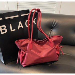 Gros plan du grand sac de voyage rouge avec cordons de serrage latéraux et rangement spacieux
