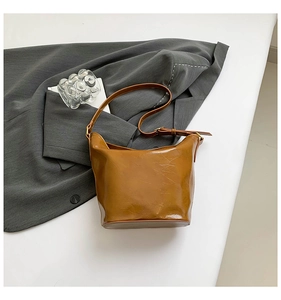 Detail of vintage brown textured leather bucket bag with gold buckles on a grey blazer