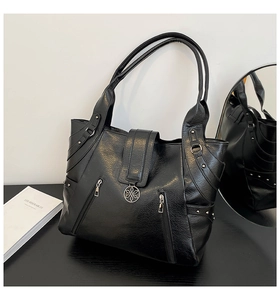 Detail view of black PU tote bag featuring decorative zippers and floral metal charm