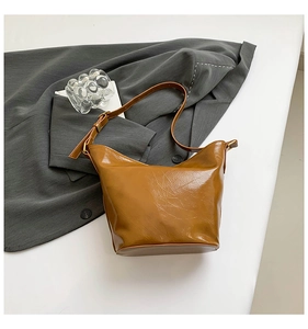 Detailed view of brown retro bucket bag with glossy cracked texture and bronze hardware