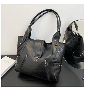 Close-up of black PU leather tote bag with silver floral pendant and decorative zippers
