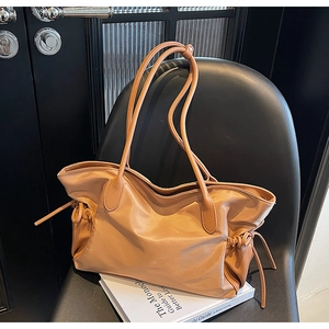 Détail du sac fourre-tout caramel avec anses en cuir et cordon de serrage sur chaise