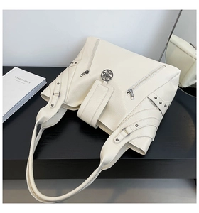 Detail of off-white faux leather tote bag with silver studs and multi-zipper pockets