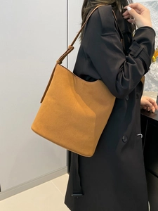 Minimalist tan suede bucket bag with adjustable strap and contrast stitching details