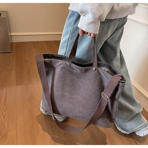 Detail showing thick canvas tote bag material and reinforced metal rivets in dark coffee brown