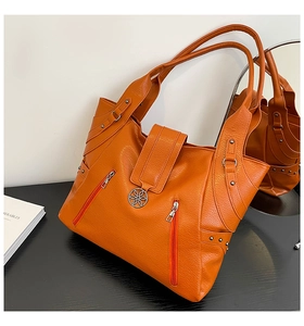 Detailed macro view of orange pebble-grain faux leather and silver zipper on tote bag