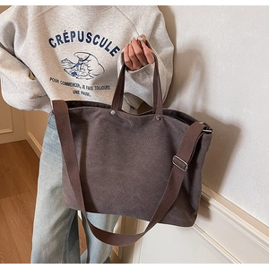 Detail view of large dark brown canvas tote bag with metal rivets and magnetic closure