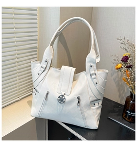 Detail of white lychee leather tote bag with silver studs and floral metal buckle