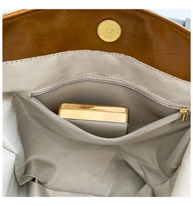 Detail view of the retro brown handbag showing herringbone lining and golden magnetic clasp