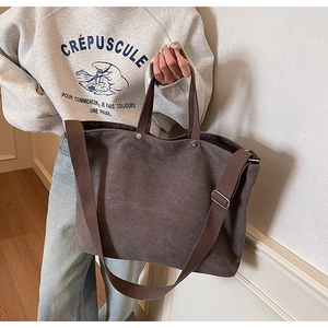 Detailed close-up of dark brown canvas tote bag with adjustable shoulder strap and metal buckle