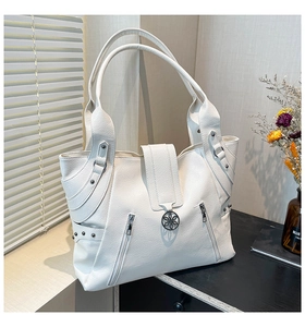 Detailed macro view of white pebble grain tote bag with decorative zippers and floral clasp