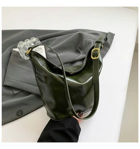 Detailed view of the dark green patent leather hobo bag with a gold buckle strap