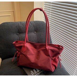 Vue détaillée du grand sac de voyage en nylon rouge foncé avec cordon sur une chaise