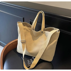 Detail of khaki canvas tote bag with adjustable strap and silver metal buckle on chair