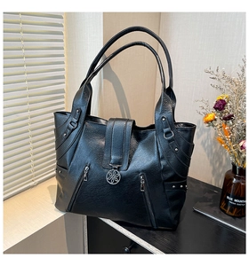 Detail of black textured faux leather tote with floral buckle and decorative zippers