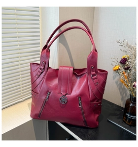 Detail of burgundy tote bag with litchi texture leather and decorative metal zippers
