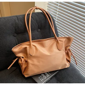 Détail du sac fourre-tout caramel montrant les poignées en cuir et le design avec cordon serré
