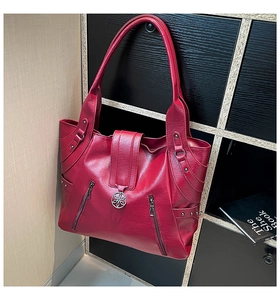 Detail of red faux leather tote bag showing double zipper design and floral metal hardware