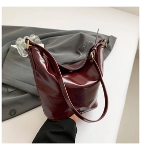 Close-up of glossy burgundy bucket bag with vintage wrinkled texture and gold buckles