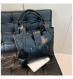 Close-up of black lychee leather tote bag with silver floral pendant and metallic rivet details
