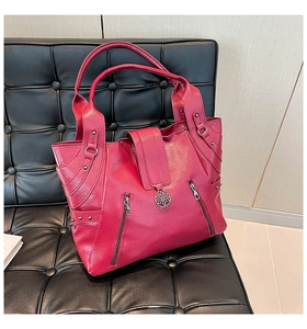 Detail of rose red tote bag featuring rivet accents and round metallic flower charm