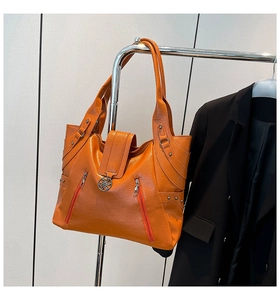 Detail of orange lychee grain leather tote with decorative zippers and metal buckle