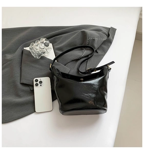 Macro detail of glossy black leather tote bag with adjustable metallic buckle strap