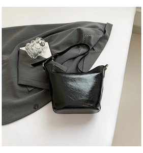 Close-up of shiny black wrinkled leather texture on a stylish bucket shoulder bag