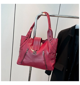 Detail view of burgundy leather tote featuring dual zipper pockets and retro metal rivets