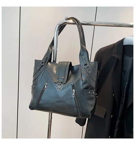 Detail of black lychee grain leather tote bag with silver flower logo and zippers
