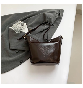 Detail of glossy dark brown oil-wax leather texture with gold metal hardware on bag