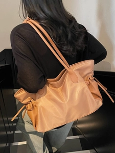 Grand sac de voyage beige porté par un mannequin dans un escalier moderne