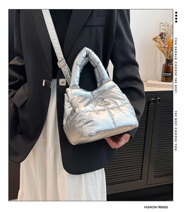 Close-up of a silver metallic quilted puffer handbag worn by a model in a modern setting