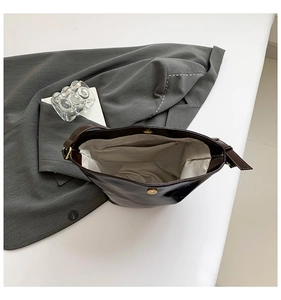 Detail of dark brown glossy shoulder bag showing interior lining and metal magnetic closure