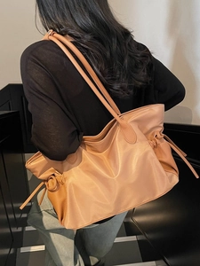 Grand sac de voyage beige en nylon et cuir avec cordon latéral sur un escalier