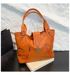 Detailed macro view of orange textured PU leather tote bag with decorative zippers