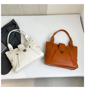 Detail view of large PU tote bags in cream and caramel with side zippers and floral logo