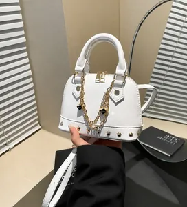 Detailansicht der weißen Muschel-Tasche mit goldenen Beschlägen und Lychee-Ledertextur