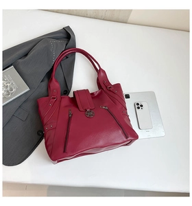 Detail view of burgundy tote bag with litchi texture, zipper decor and metal flower charm