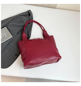 Close-up of wine red PU tote bag featuring lychee texture and metal rivet details
