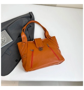 Detail of orange lychee grain PU leather tote bag with metal zipper and rivet accents