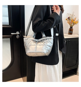 Silver quilted puffer bucket bag shown on shoulder in a stylish modern interior setting