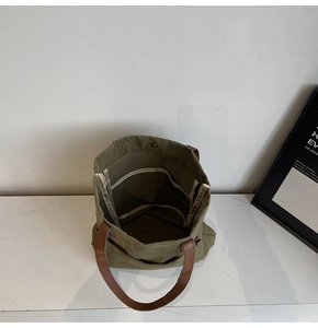 Detail of dark green canvas tote showing interior compartment and metal snap button
