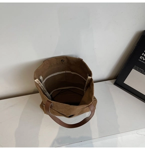 Detailed interior of brown canvas tote bag with leather handles and metal snap closure
