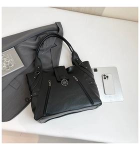 Close-up of black PU tote bag with floral magnetic clasp and diagonal zippers for women