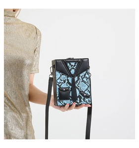 Detail of creative suit-style crossbody bag with blue snakeskin texture and lapel design