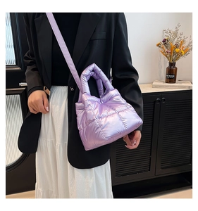 Close-up of a purple metallic quilted puffer bag with crossbody strap on a female model