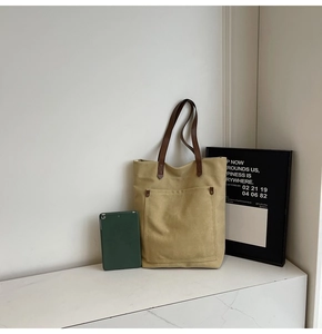 Close-up of khaki canvas tote bag with leather straps and metal rivet detail